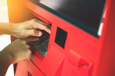 Man covering the keypad at the ATM to avoid ATM skimming.