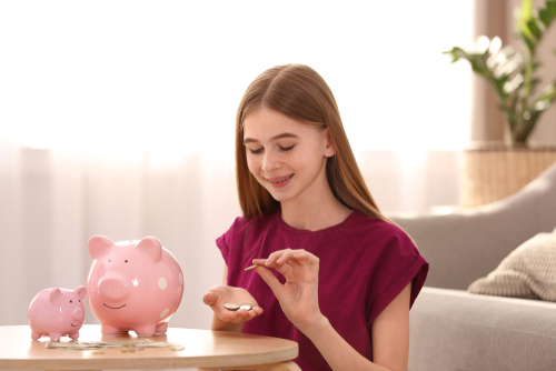 Teen girl counting her money from her piggy bank; financial tips for teens.