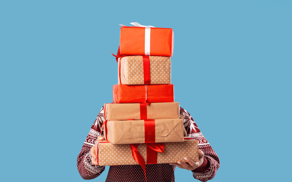 Person holding a stack of gifts worrying about their holiday savings