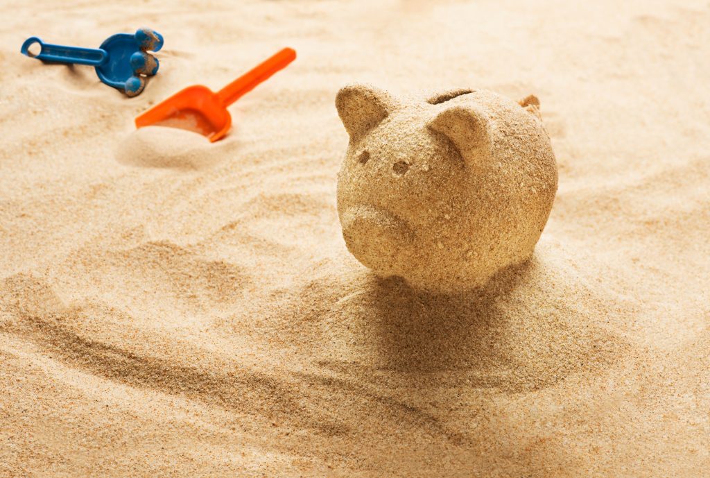 A piggy bank 'sand castle' on a relaxing beach holding your vacation savings