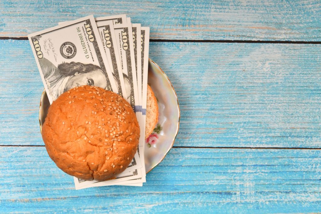 A burger made of money on a picnic table in spring - a symbol of the best savings rates available before big changes come.