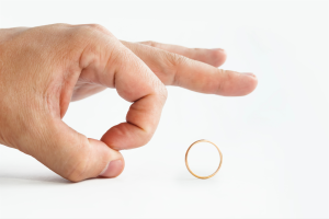 Financial planning and divorce can be a layered subject. Image of a finger flicking away a wedding ring - good riddance!