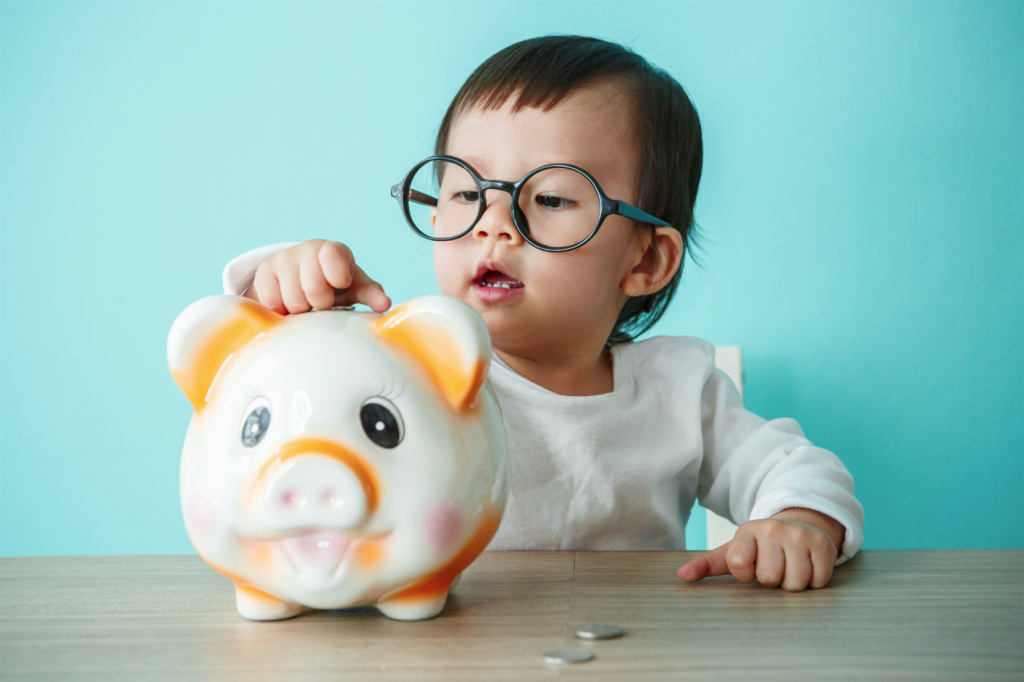 Can you take out a 529 plan for grandchildren? A very young girl with glasses filling up an adorable piggy bank.