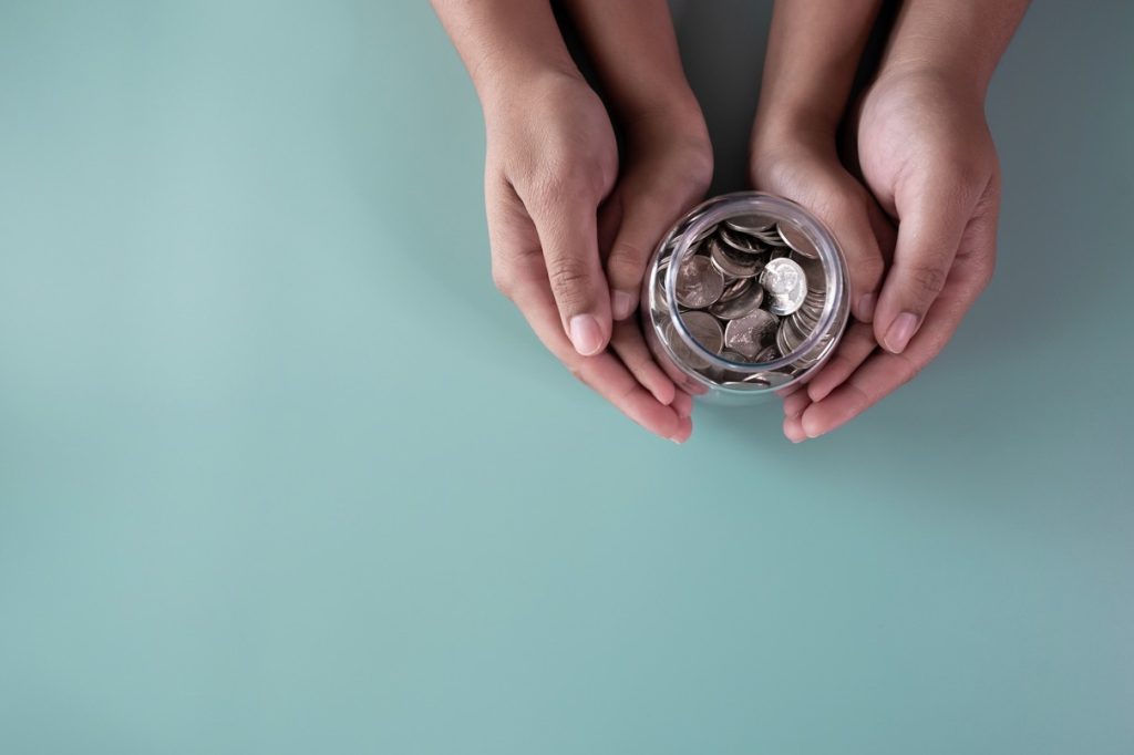 A parent and child holding a jar of their savings, saving up either for a Trump account or a 529 Plan